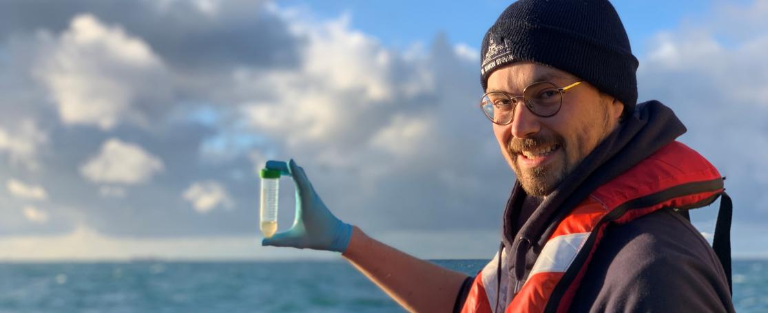 Michiel aan boord van RV Simon Stevin met een waterstaal voor metagenomics analyse